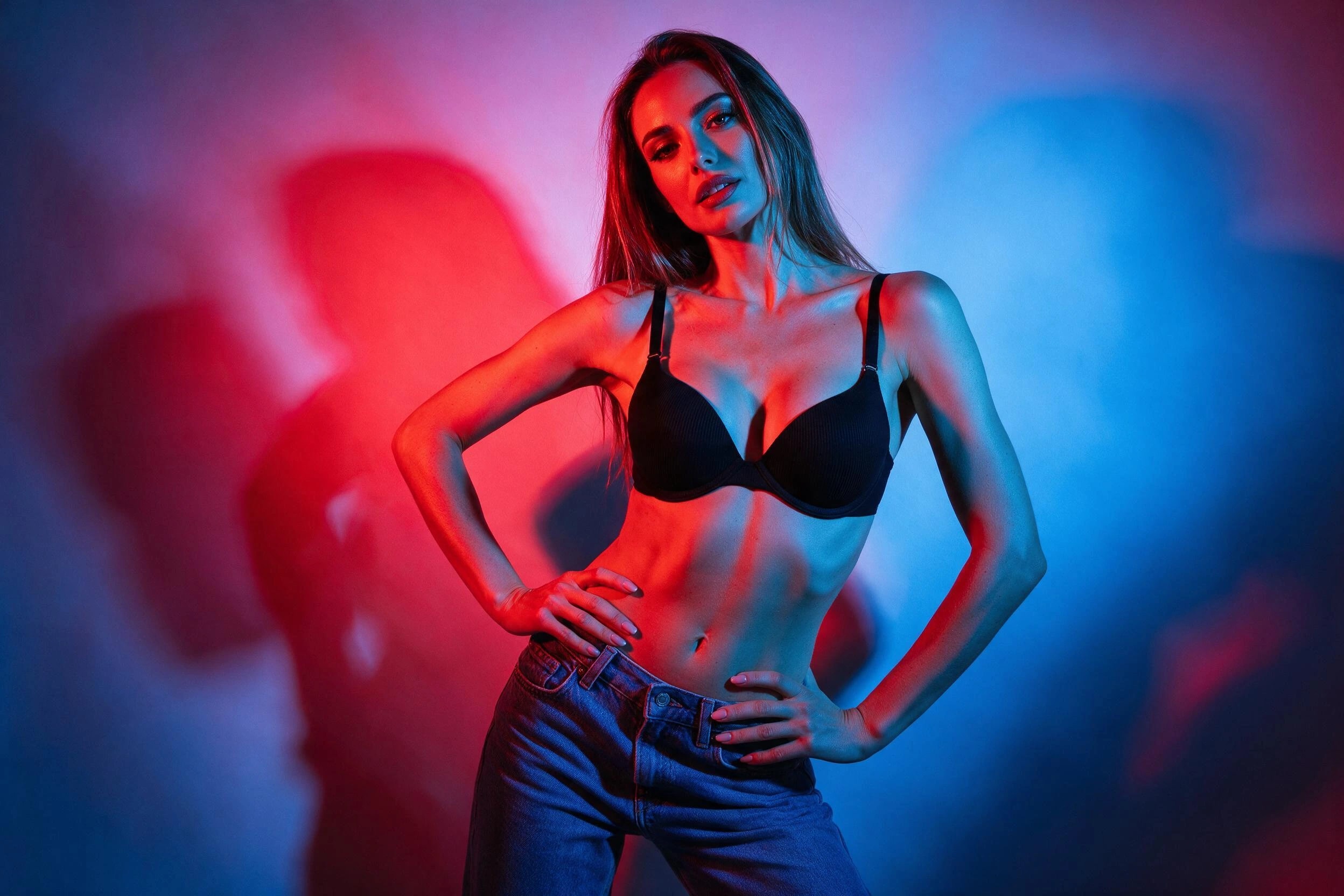 Photoreal render of a woman in a black bra and jeans in a photo studio with colored gel lights, generated on Creamify's Dream engine